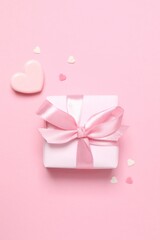 Beautiful gift box with pink hearts on color background