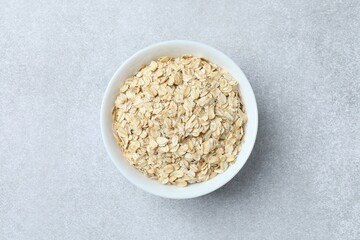 Composition with oatmeal flakes on gray background. Cooking breakfast