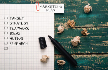 Black marker sits on a piece of paper with a marketing plan written on it