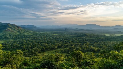 Obraz premium Lush green landscape with rolling hills and distant mountains under a cloudy sky