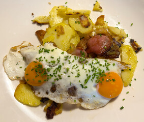 Delicious traditional Tyrolean mountain dish with cut grilled potatoes, speck and eggs. View from the top. Calorie dish