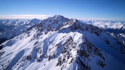 Majestic snow covered mountain peaks with clear blue sky and distant mountain ranges on horizon