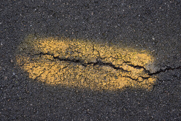 Black pavement with yellow painted stripe