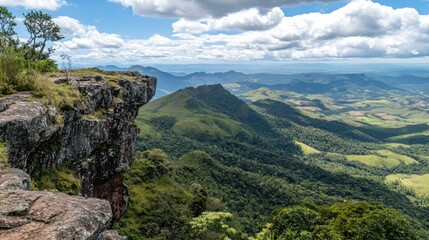 Naklejka premium Panoramic mountain view from a rocky cliff with green rolling hills below on a summer day