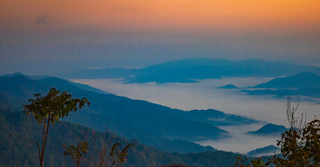 The stunning view from a tourist's standpoint as they go down a hill on a foggy trail with a hill...