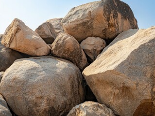 A collection of large smooth rocks or boulders piled on top of each other under a clear blue sky