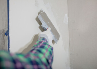 Master working with plasters on white walls and putty screeds after installing drywall. Closeup....