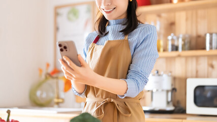 キッチンでスマホを使う笑顔の女性