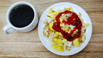 Healthy breakfast with scrambled eggs with ketchup sauce and coffee cup on the wooden table. 