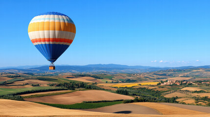 Obraz premium vintage style hot air balloon floats gracefully over picturesque landscape, showcasing rolling hills and vibrant fields under clear blue sky. scene evokes sense of adventure and tranquility