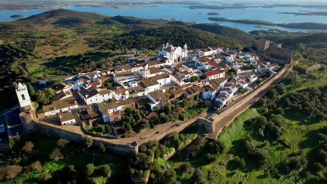 Aerial high angle 4k video of Monsaraz medieval village and castle, Alentejo, Portugal. Fortified hilltop town with white houses at Alqueva lake. Scenic historic landmark in Evora district, Europe.
