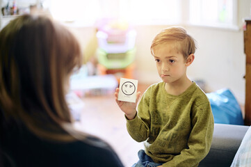 Therapy, emotion and boy talking to a therapist while sitting on a sofa in a psychology clinic....