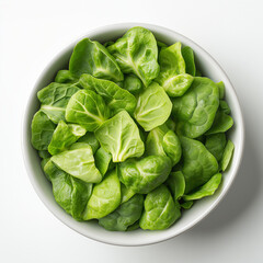 Obraz premium Bowl of green leafy vegetables. The bowl is white and filled with greens. The greens are cut into small pieces
