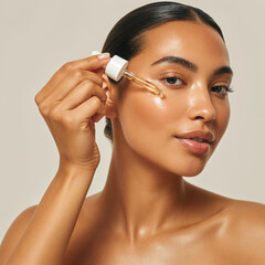 A tan young woman with flawless, radiant skin applying a skincare serum to her face