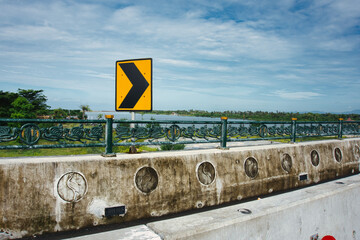 Curved Road Sign on a Bridge with Ornate Metal Railings