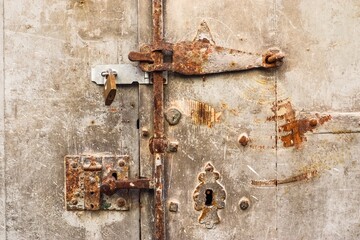 Old rusty metal door with latch and padlock is closing