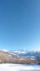 A breathtaking wide-angle view of snowy mountains basking under a clear blue sky, creating a tranquil and majestic landscape.