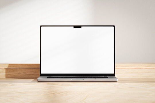 Opened laptop with blank white screen on the wooden desk