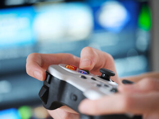 A teenager playing video games using a gamepad. Shallow depth of field. Close up.