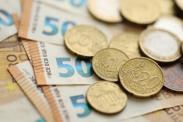 Many cent coins of euro currency lies on many fifty euro bills banknotes