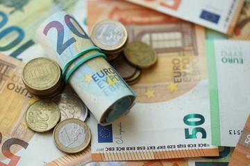 Roll of euro currency money bills and many euro cents on banknotes of european union