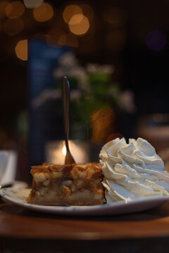 Piece of apple pie with whipped cream on the side, on a table in a restaurant 