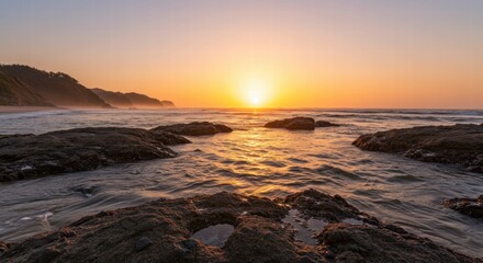 A serene sunset over a rocky beach, with waves gently lapping at the shore, creating a peaceful and picturesque coastal scene