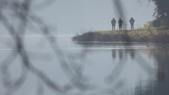 people in silhouette walking on the banks of the adda river.