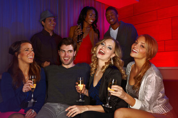 Cheers, party and portrait of people on sofa with alcohol for celebration, nightclub or happy hour together. Vip, relax and group of friends drinking champagne at social event for reunion on weekend.