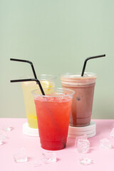 Three takeaway cups of summer drinks with ice. Lemonade on colored background