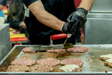 latin man preparing hamburgers on the grill in the streets of the city of la paz in bolivia - gastronomy concept