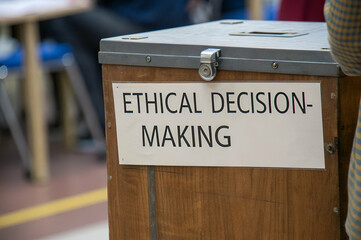Business Ethics, A wooden box labeled "Ethical Decision-Making" stands in a classroom, highlighting the importance of morality in choices.