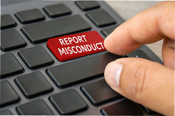 Business Ethics, A hand is about to press a red button labeled "REPORT MISCONDUCT" on a black keyboard, symbolizing the act of reporting inappropriate behavior.