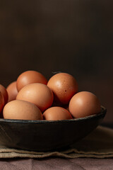 Brown chicken eggs in round wooden bowl,  perfect for Easter, natural light 