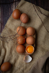 Brown chicken eggs in wooden base on dark background, perfect for easter, natural light  
