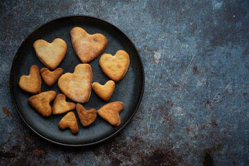 Cookies in the shape of heart baked for St Valentines day on dark blue background 