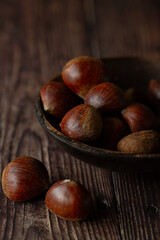 Chestnuts in a wooden brown bowl on a brown background 