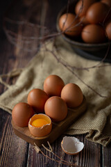 Brown chicken eggs in wooden base on dark background, perfect for easter, natural light  