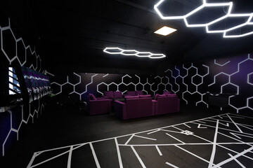 Room with dark blue walls and purple sofas around a black table