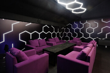 Room with dark blue walls and purple sofas around a black table