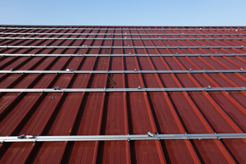 Aluminum Mounting Structures Being Installed on a Red Metal Roof for Future Solar Panels