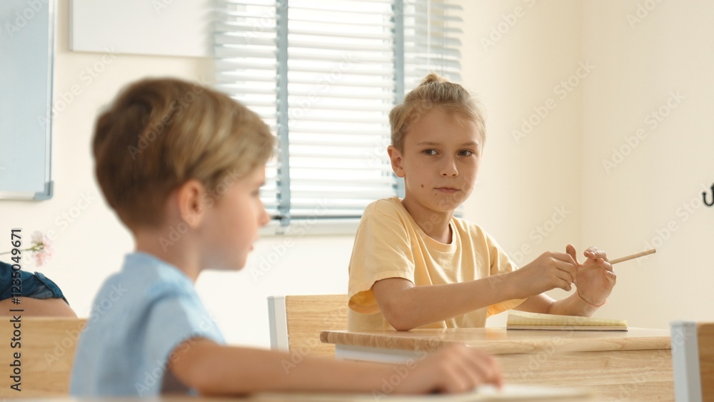 Poster beautiful teacher explaining test while caucasian boy doing classwork and listening explanation. cut
