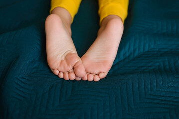 Children's feet and heels on a dark blue bed. Importance of sleep for babies. Sleep mode babies 5 y.o
