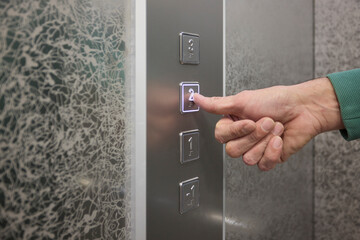 Pressing the elevator button in contemporary high rise buildings signifies modern urban convenience