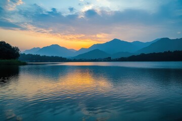 Sunset reflecting on calm lake with mountains in the background near tranquil nature setting