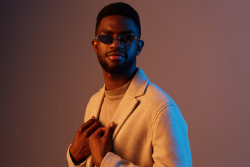 Stylish young man in sunglasses wearing a smart casual outfit, posing confidently against a gradient background, evoking modern fashion and self expression