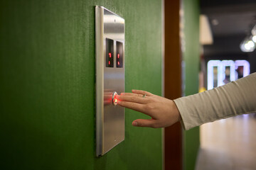 Pressing the elevator button in contemporary high rise buildings signifies modern urban convenience