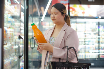woman shopping for orange juice in grocery store, holding bottle. Healthy food lifestyle weight loss
