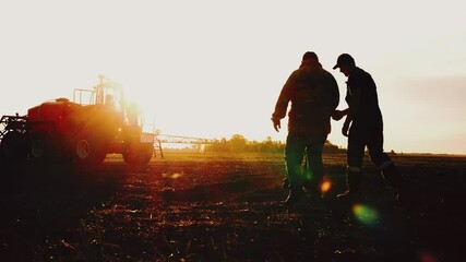 Silhouette of three farmers or tractor workers hand shake for successful deal and agreement in agricultural business, meeting on field at sunset. Agronomists discuss rural machinery, teamwork