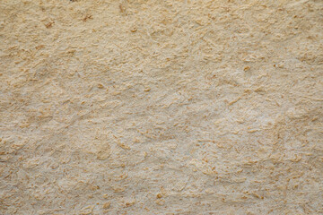 Interesting and curious textured background of the light beige wall of the building